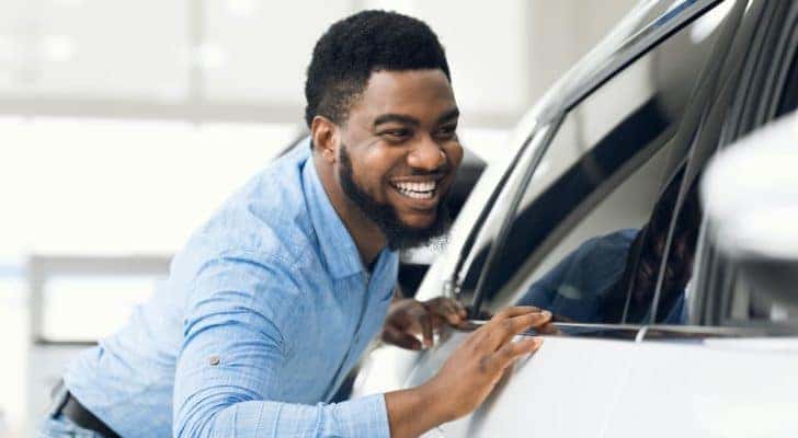 A man is smiling looking at new Chevy vehicles in stock.