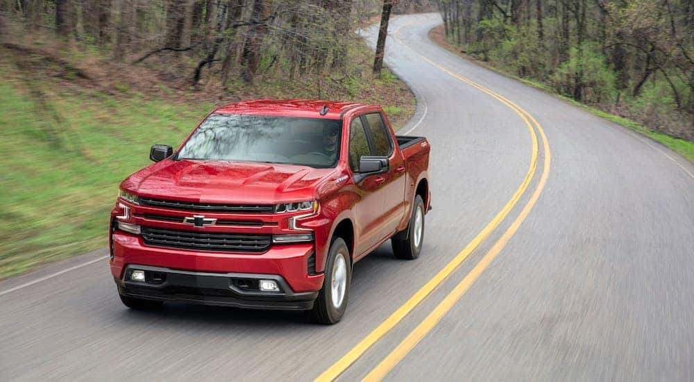 A red 2019 Chevy Silverado RST is shown driving down a winding road after leaving an Atlanta used truck dealer.