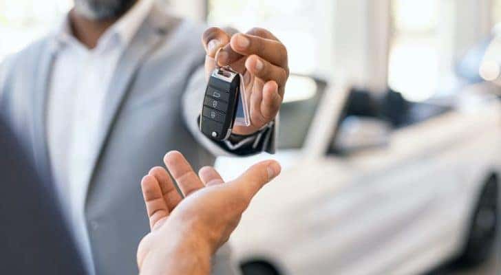A salesman is holding out a set of keys at a Chevrolet dealer in Atlanta.