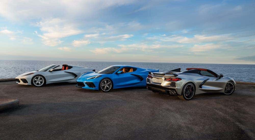 A silver, a white, and a blue 2021 Chevy Corvette are shown parked on a jetty.