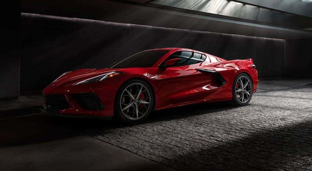 A red 2021 Chevy Corvette is shown in low lighting parked in a warehouse.