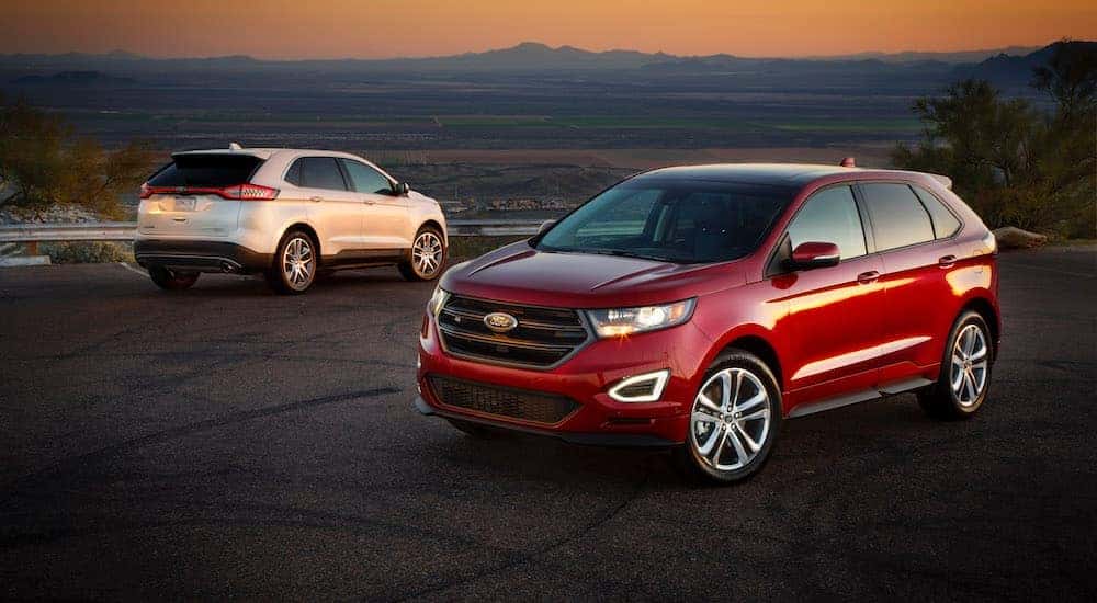 A red and a white 2015 Ford Edge are shown parked in an empty parking lot.