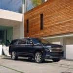 A black 2022 Chevy Suburban is shown parked outside of a modern home.