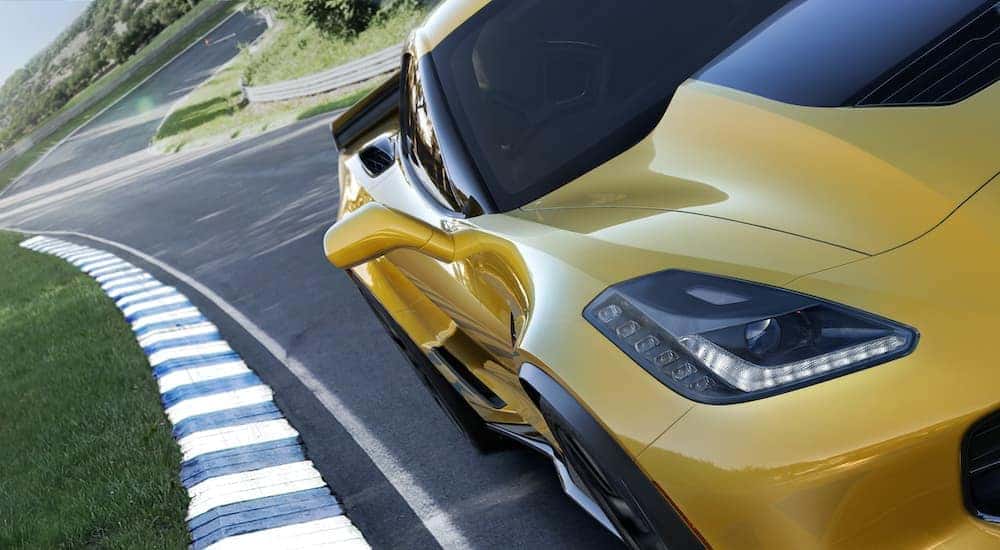 A close up shows the passanger side headlight on a yellow 2015 Chevy Corvette Z06 while driving on a race track.
