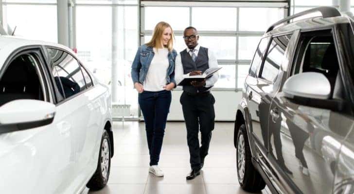 A car salesman is shown speaking to a customer at an Atlanta certified pre-owned Chevy dealer.
