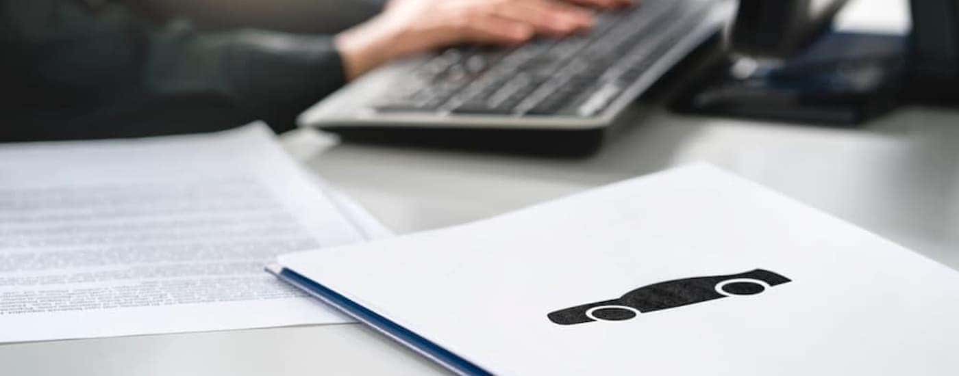 Paperwork is shown on a desk at a car dealership.