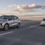 A silver 2022 Chevy Bolt EUV and a light blue Bolt EV are shown driving down a highway.