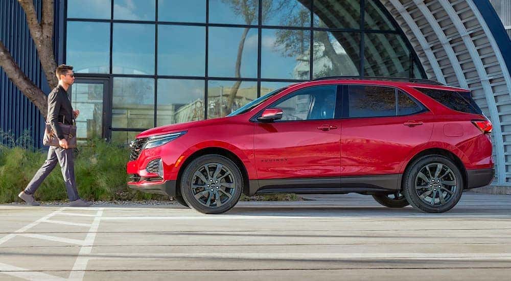 A red 2022 Chevy Equinox RS is shown in front of a modern building after leaving a Sugar Hill Chevy dealer.