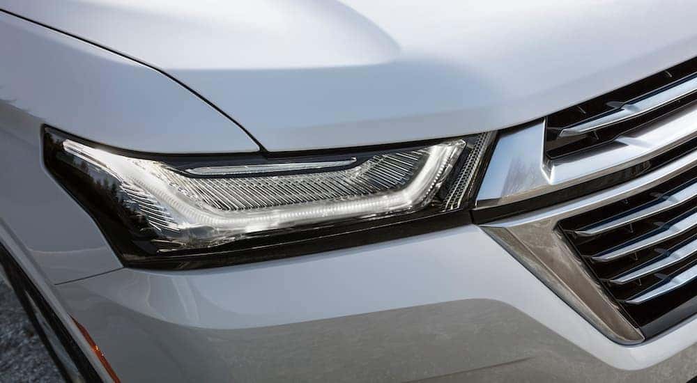 A close up shows the passenger side headlight on a white 2022 Chevy Traverse Premier.