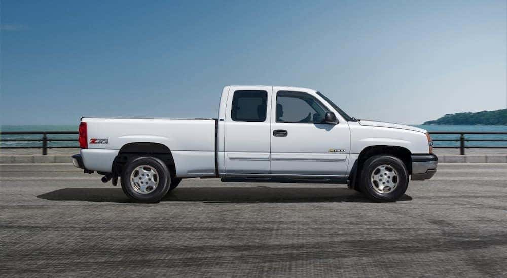 A white 2006 Chevy Silverado 1500 is shown from the side driving over a bridge.