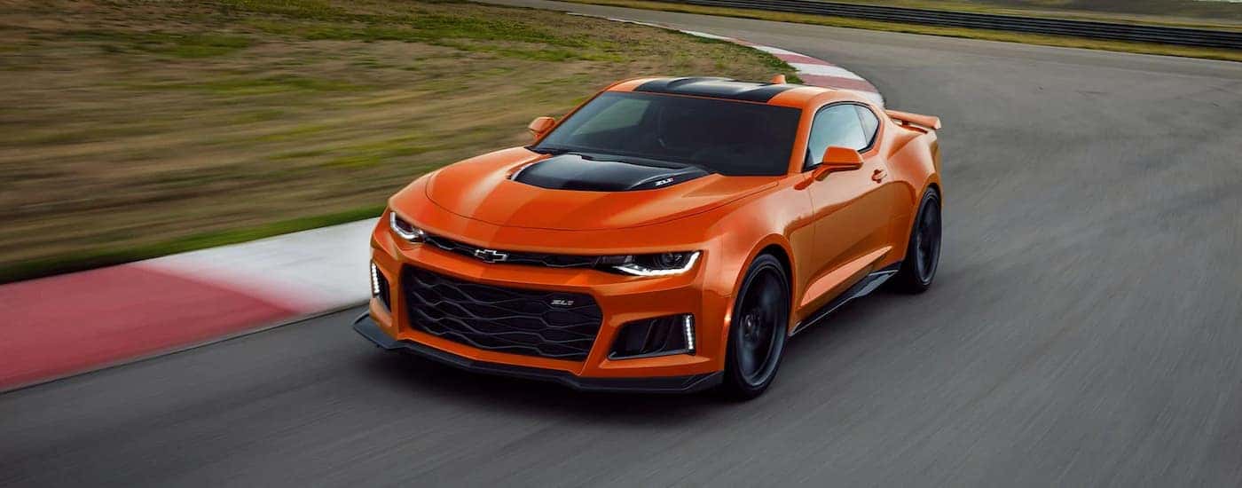 An orange 2022 Chevy Camaro ZL1 is shown driving on a racetrack.