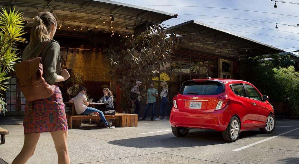 A red 2022 Chevy Spark LT is shown from the rear parked outside of a shop.