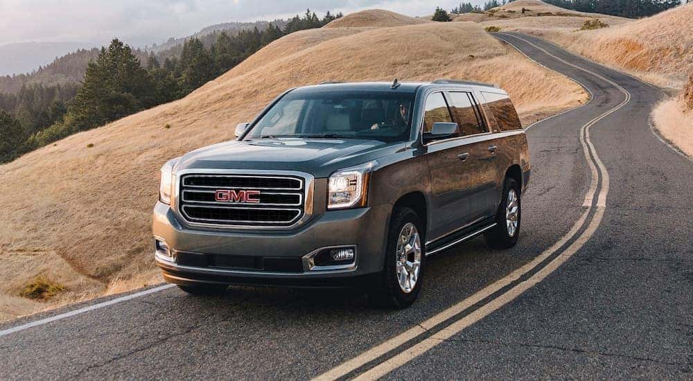 A grey 2020 GMC Yukon is shown from the front driving on an open road.