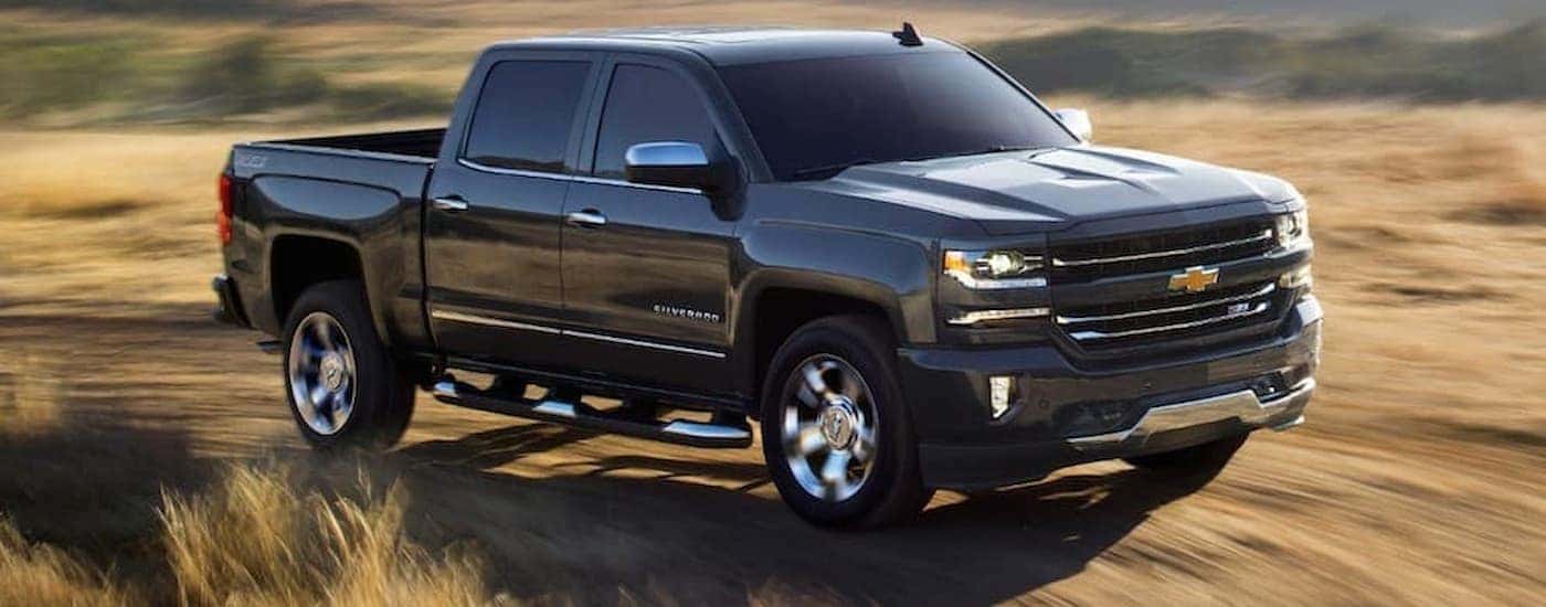A black 2018 Chevy Silverado 1500 is shown driving on a dirt trail.