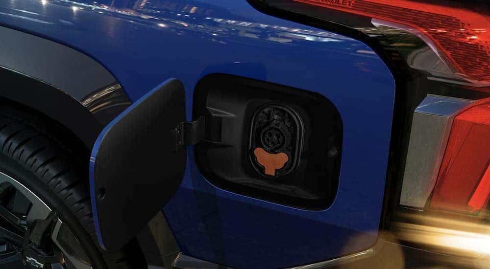 A blue 2024 Chevy Silverado EV shows the charging port in close up at a Lawrenceville Chevrolet dealer.
