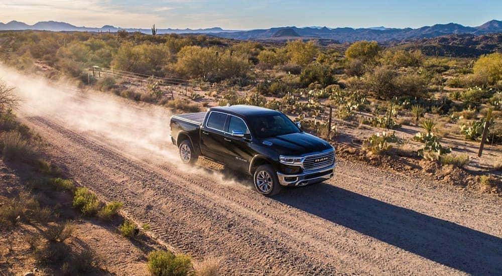 A black 2019 Ram 1500 is shown from the front at an angle while it drives down a dirt road.