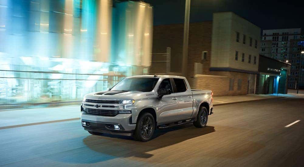 A white 2020 Chevy Silverado 1500 is shown from the front at an angle while it drives down a city street after leaving a Atlanta used truck dealer.