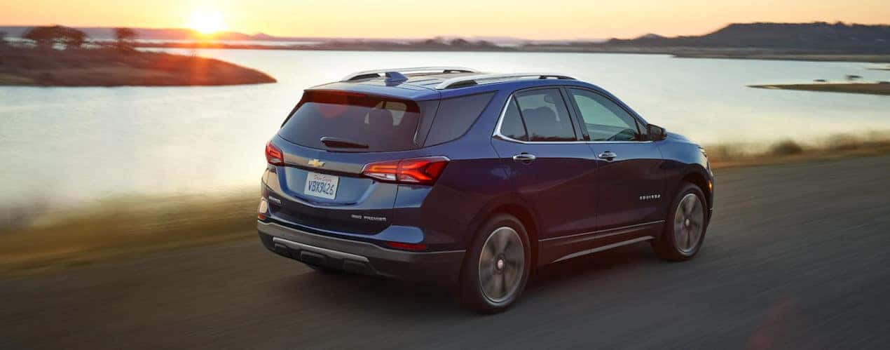 A blue 2022 Chevy Equinox is shown from the rear driving on an open road.