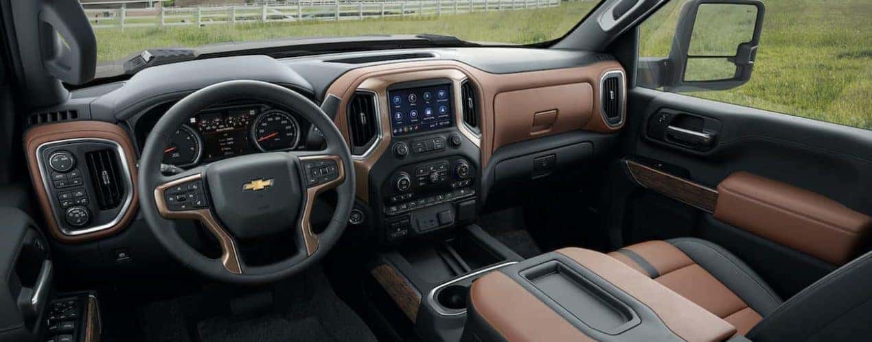 The black and brown interior of a 2022 Chevy Silverado 3500 HD shows the steering wheel and infotainment screen.