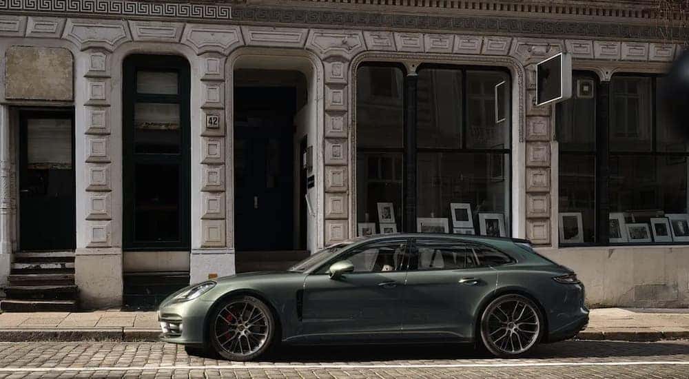 A green 2022 Porsche Panamera is shown from the side parked in front of a city building.