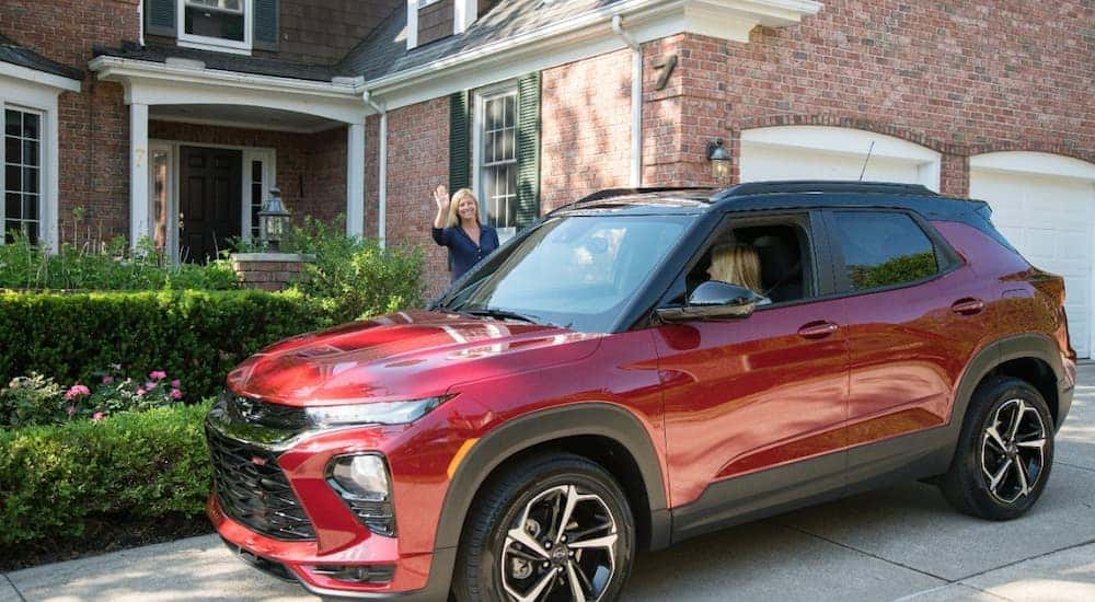 A driver is shown in a red 2021 Chevy Trailblazer parked in a driveway.
