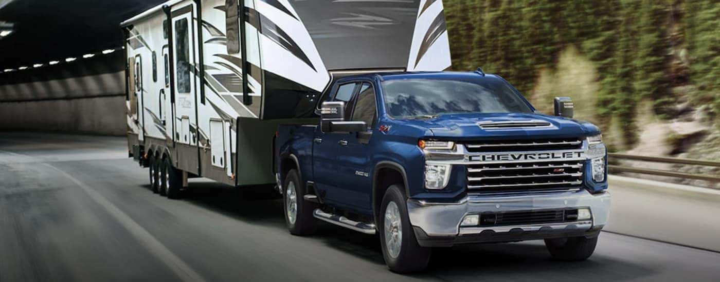 A blue 2021 Chevy Silverado 2500 HD is shown towing a trailer.