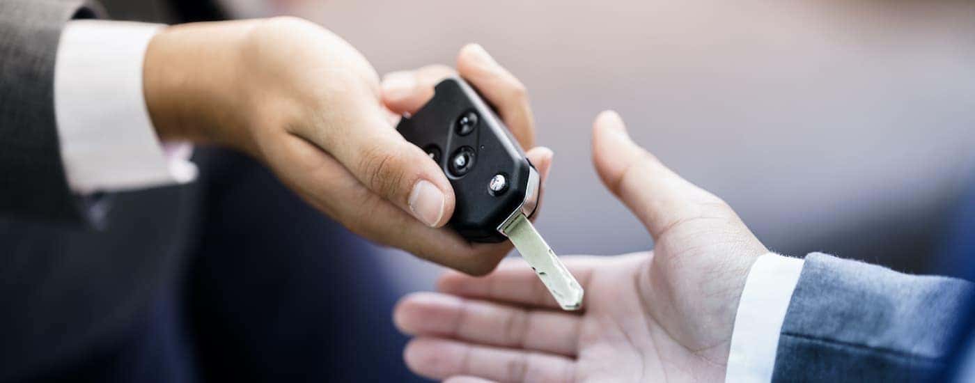 A person is shown passing a car key.