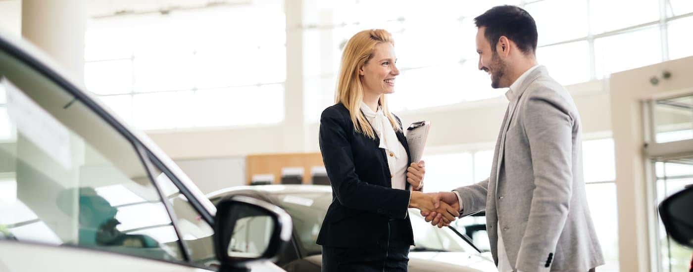 A customer is shown talking to a salesperson about selling their car.