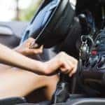A person is shown driving a manual car after searching 'used car dealership near me.'