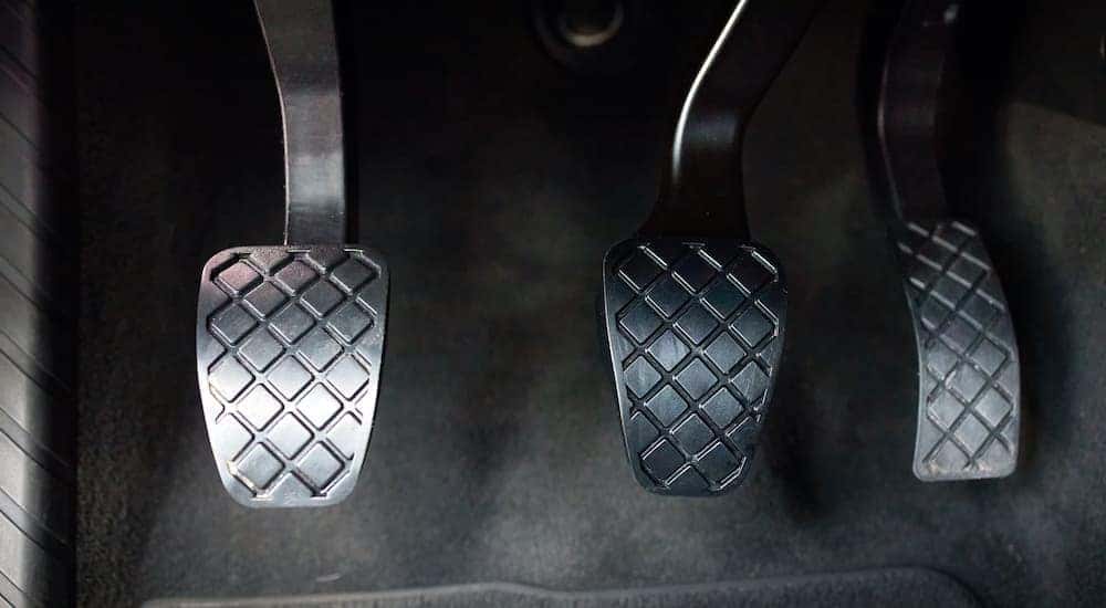 A manual car shows the pedals in close up.