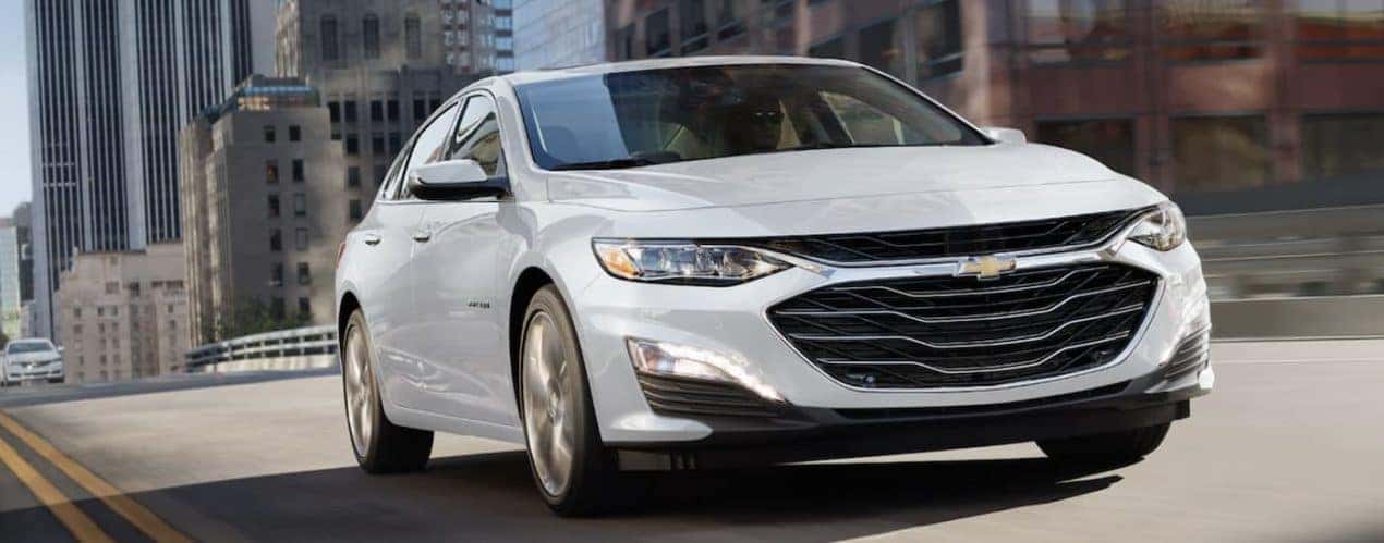 A white 2022 Chevy Malibu is shown driving on an open road.