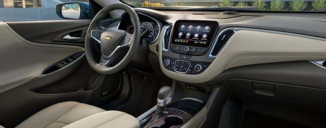 The tan interior of a 2022 Chevy Malibu shows the center console and steering wheel.