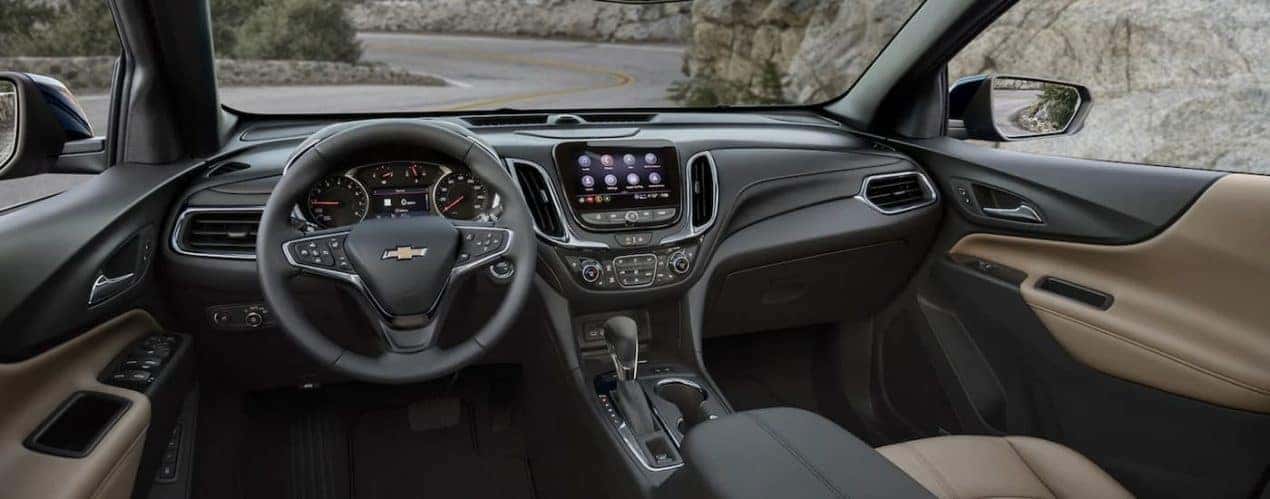 The grey interior of a 2023 Chevy Equinox shows the steering wheel and infotainment screen.