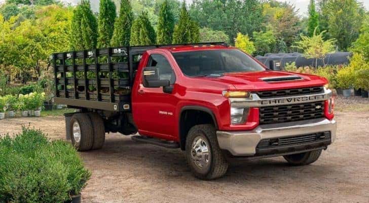 A red 2021 Chevy Silverado 3500 HD Chassis Cab is shown parked at a plant nursery.