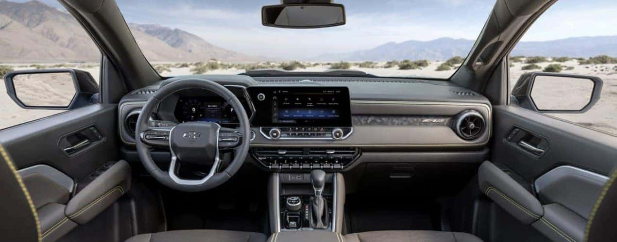 The grey interior of a 2023 Chevy Colorado ZR2 shows the steering wheel and infotainment screen.