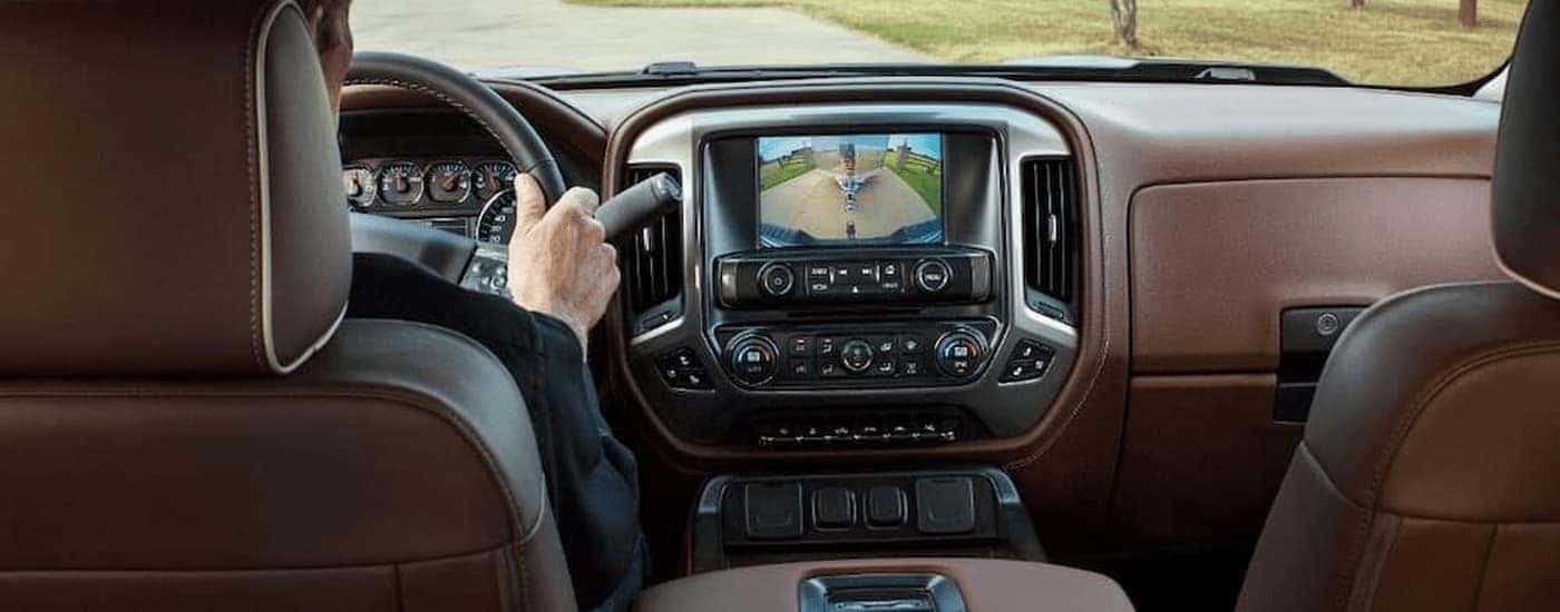 A person is shown driving a 2018 Chevy Silverado 1500 High Country on a dirt road.