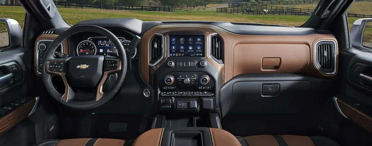 The black and brown interior of a 2023 Chevy Silverado 3500 HD shows the steering wheel and infotainment screen.