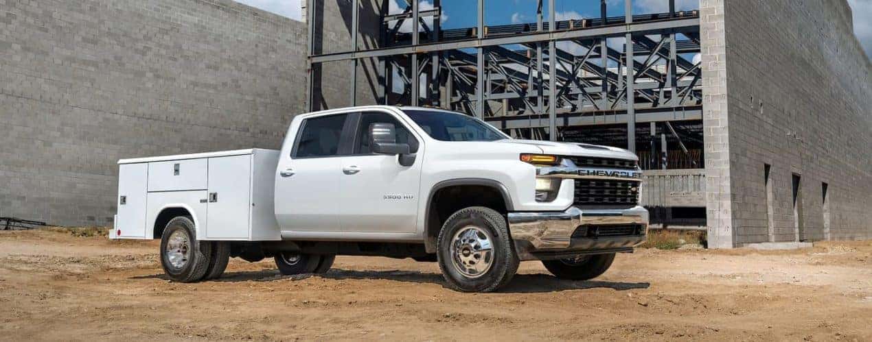 A white 2023 Chevy Silverado 3500 HD Chassis Cab is shown parked at a construction site.