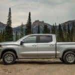 One of the most popular used trucks for sale, a silver 2020 Chevy Silverado 1500 LT, is shown from the side on a dirt trail.