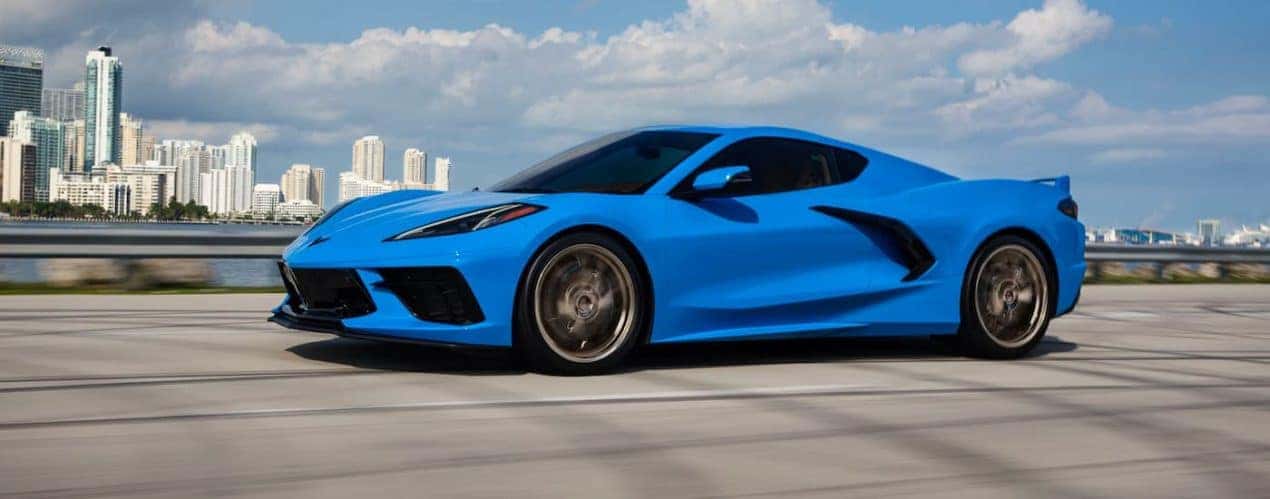 A blue 023 Chevy Corvette Stingray 3LT is shown driving past a lake and city.