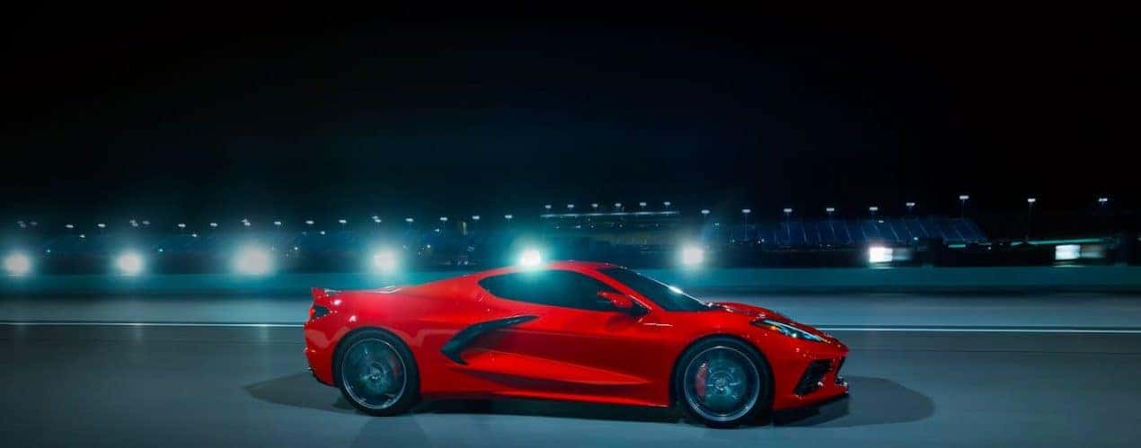 A red 2023 Chevy Corvette Stingray is shown from the side on a racetrack.