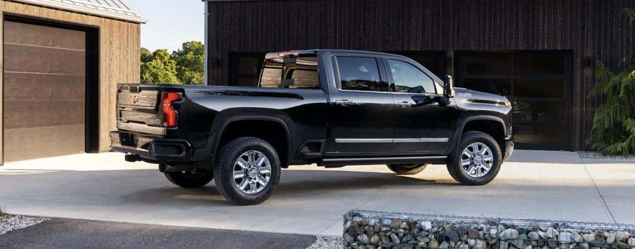 A black 2024 Chevy Silverado 2500 HD is shown form the side parked in a highway.