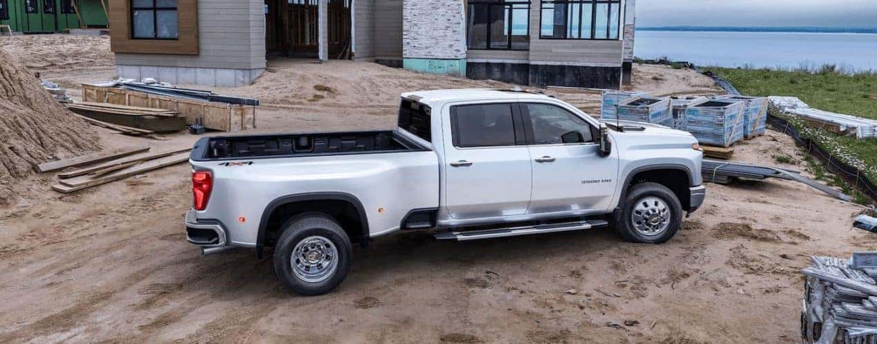 A white 2024 Chevy Silverado 3500 HD is shown from the side at a construction site.