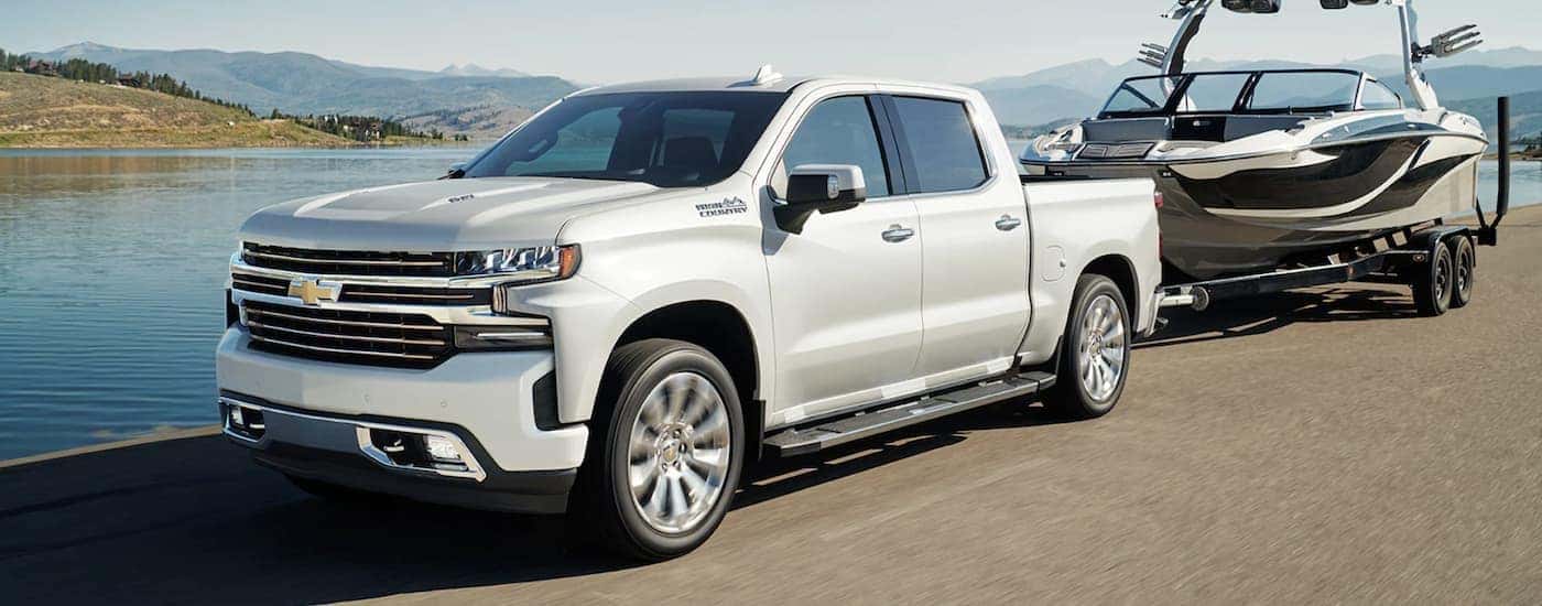 A popular truck for sale, a white 2022 Chevy Silverado 1500, is shown towing a boat.