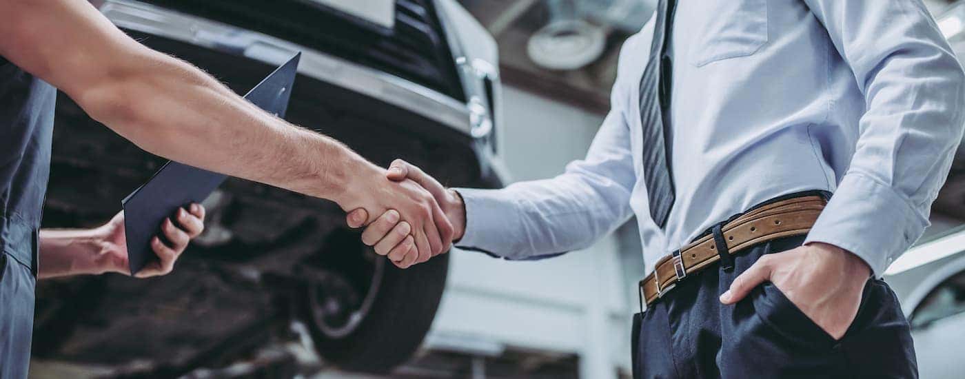 A mechanic is shown shaking hands with a customer.