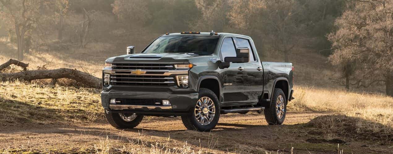 A black 2023 Chevy Silverado 2500 HD High Country is shown parked in a dry grassy field.