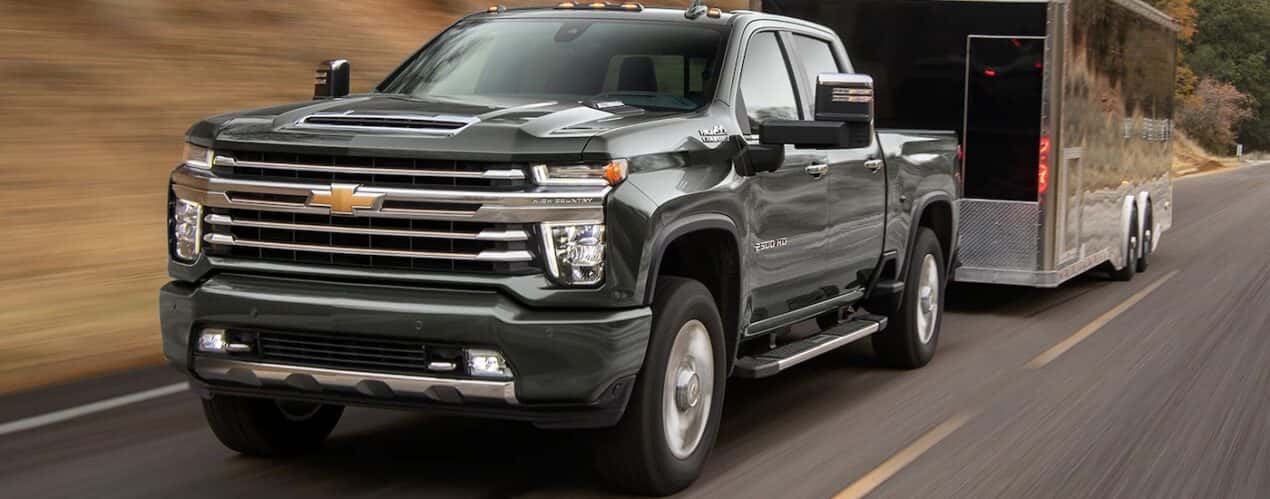 A black 2023 Chevy Silverado 2500 HD High Country is shown towing a trailer during a 2023 Chevy Silverado 2500 HD vs 2023 Nissan Titan XD comparison.