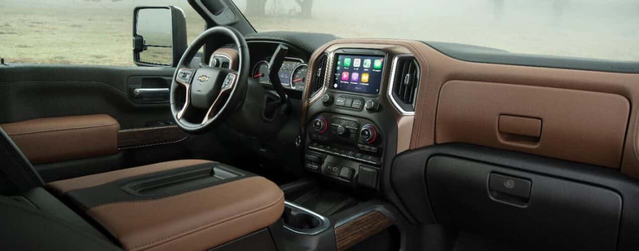 The black and brown interior of a 2023 Chevy Silverado 2500 HD shows the steering wheel and center console.