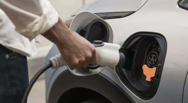 A person is shown plugging in a white 2023 Chevy Bolt EUV.