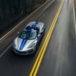 A silver 2024 Chevy Corvette E-Ray 3LZ is shown from high angle on a tree-lined road after looking electric vehicles for sale.